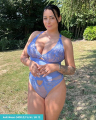 Woman wearing a blue lace lingerie set outdoors with greenery in the background