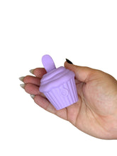 Hand holding a purple silicone cupcake-shaped item against a white background