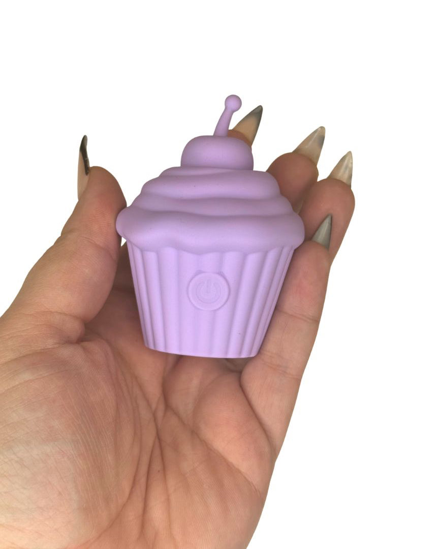 Hand holding a purple cupcake-shaped discrete sex toy with a white background