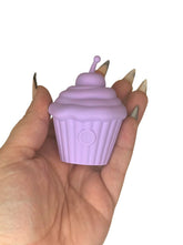 Hand holding a purple cupcake-shaped discrete sex toy with a white background