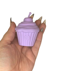 Hand holding a purple cupcake-shaped discrete sex toy with a white background