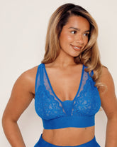 Woman wearing a blue lace bralette against a plain background