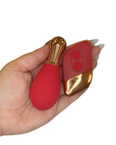 Red and gold object held in a hand on a white background