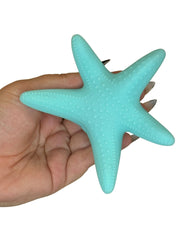 Turquoise starfish held in a hand against a white background