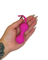 Hand holding a pink ball with a small attachment on a white background