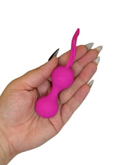 Pink silicone ball with a loop held in a hand on a white background