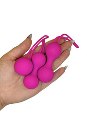 Hand holding three pink ball-shaped objects with strings against a white background
