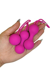 Hand holding three pink ball-shaped objects with strings against a white background