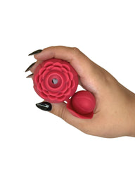 Hand holding a red silicone flower-shaped product on a white background