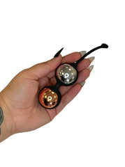 Hand holding a small metallic object with a reflective surface on a white background
