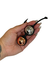 Hand holding a small metallic object with a reflective surface on a white background