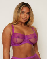Woman wearing a purple bra and panties set against a plain background