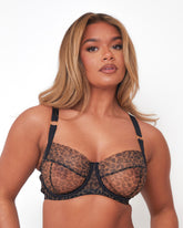 Model wearing Tutti Rouge Shania Bra in Wild Leopard, with sheer leopard print cups, underwiring and black straps with gold rings.