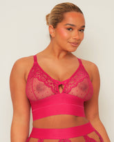 Woman wearing a pink lace and spot mesh bralette against a white background