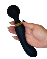 Black handheld massager with gold accent held by a hand on a white background
