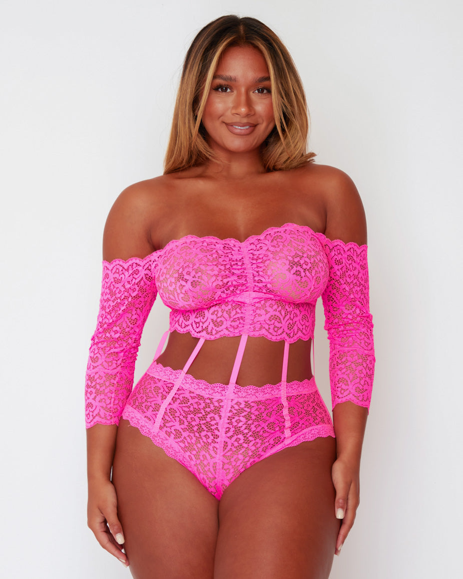 Full front view of the Alix Bodysuit in Pink, featuring a bandeau-inspired lace bust, long lace sleeves, decorative waist straps, and a high-leg fit designed to enhance curves.