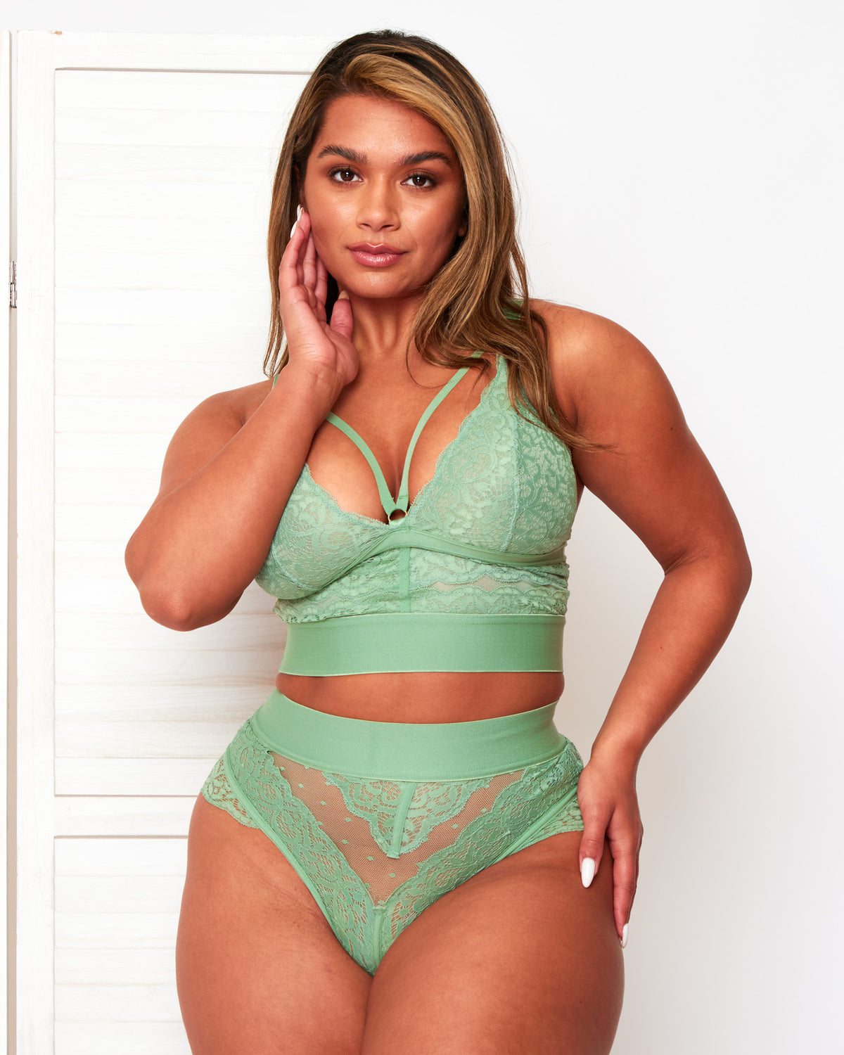 Model wearing the Tutti Rouge Gia Basil Green lace bralette with neckline straps and a matching high-waisted lace thong.