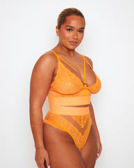 Side view of the Tutti Rouge Gia Sunburst Orange lace bralette and matching high-waisted thong, showing sheer mesh panels.