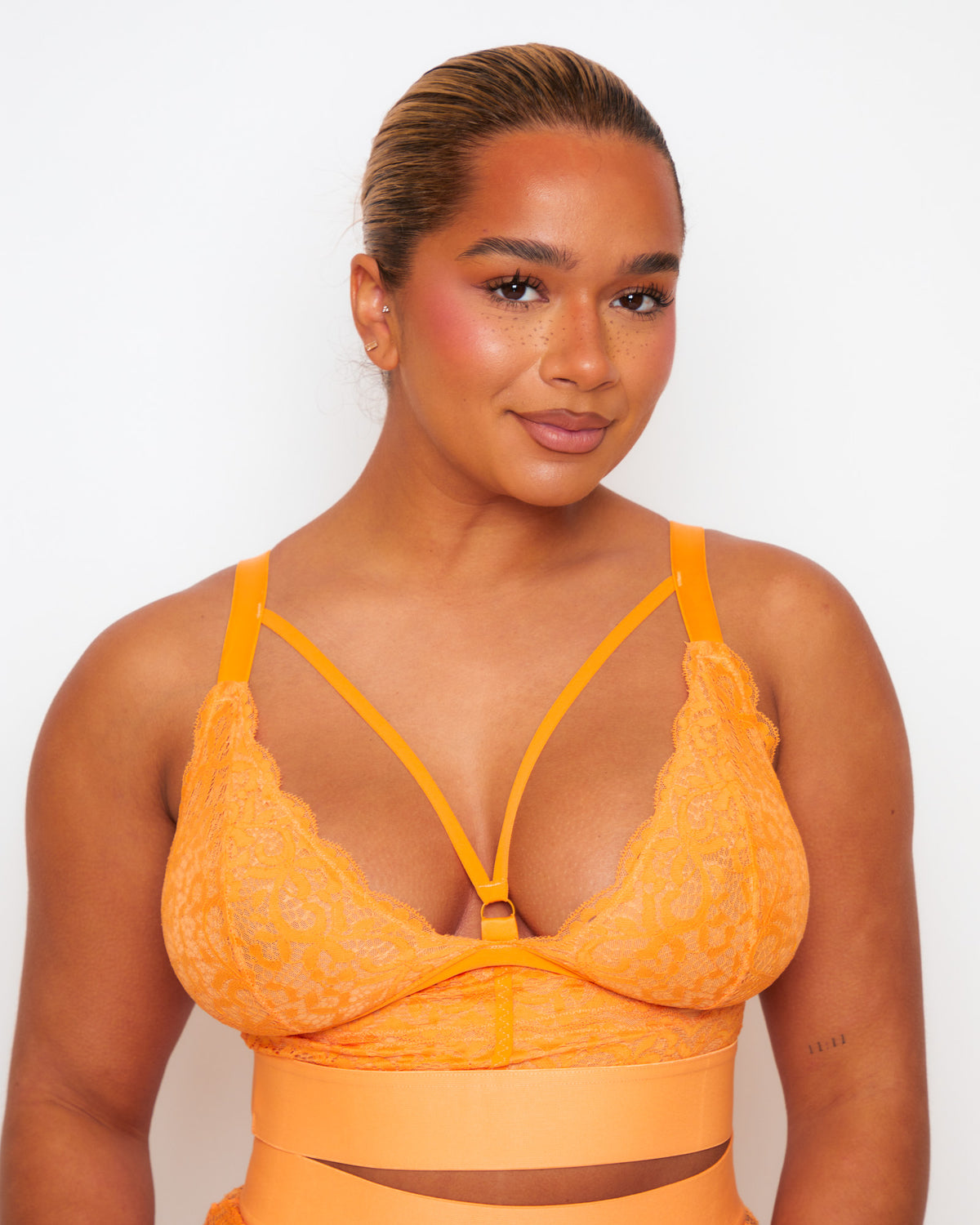 Front close-up of the Tutti Rouge Gia Sunburst Orange bralette with scalloped lace cups, a strappy neckline and central gold-tone ring.