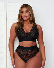 Model wearing the Hallie Bralette and High Waist Brief in Black by Tutti Rouge, highlighting sheer floral lace cups, a deep V-neckline, and a flattering high-waisted silhouette.