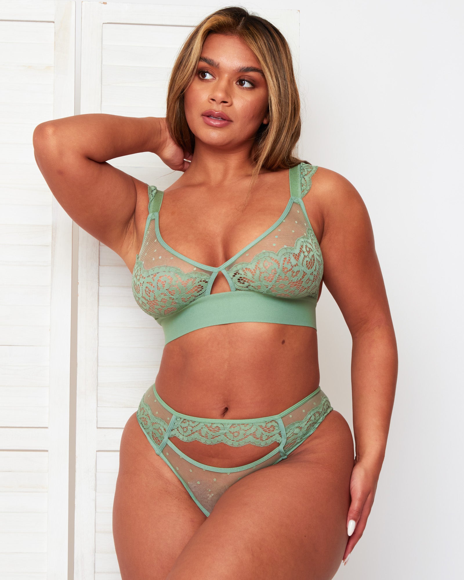 Model wearing the Tutti Rouge Kaitlin Basil Green lace and mesh bralette with matching cut-out briefs, one arm raised.