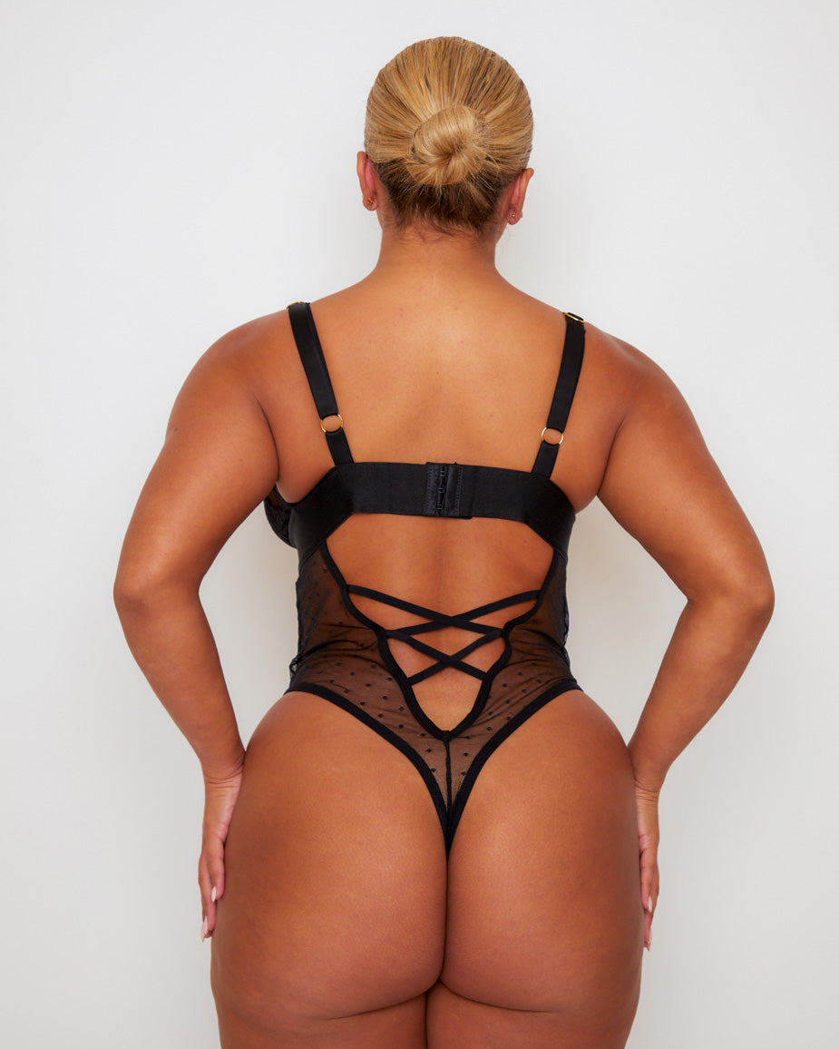 Back view of the Tutti Rouge Stormy Bodysuit in Midnight Black showcasing an open back with lace-up detailing, adjustable straps and sheer mesh thong silhouette.