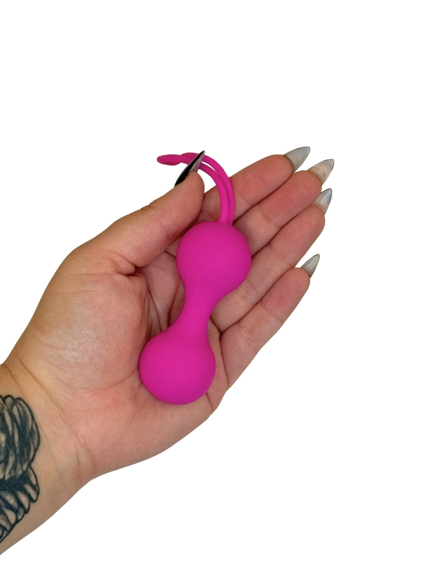 Hand holding a pink ball with a small attachment on a white background