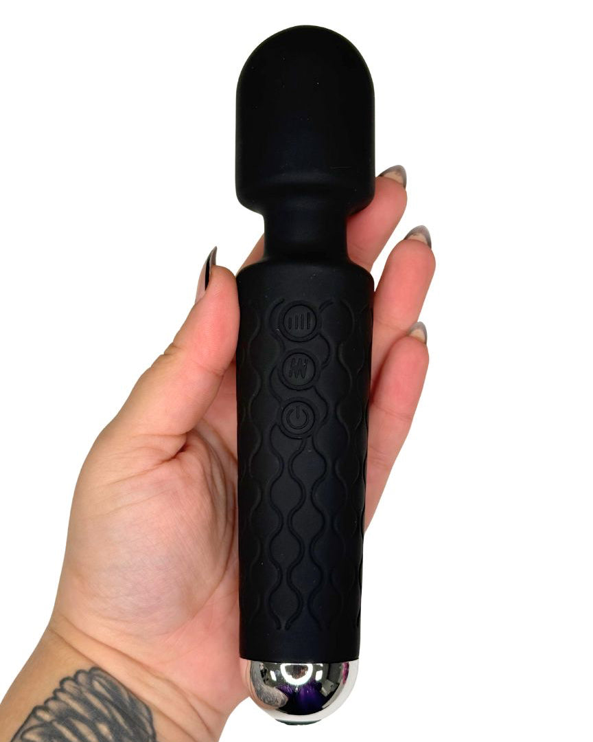 Black handheld massager held in a hand on a white background