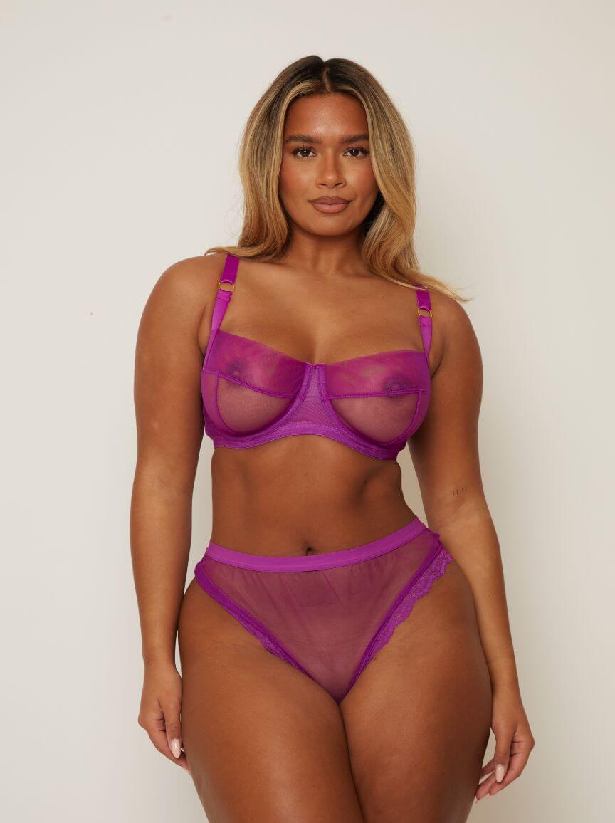 Woman wearing a purple lingerie set against a plain background