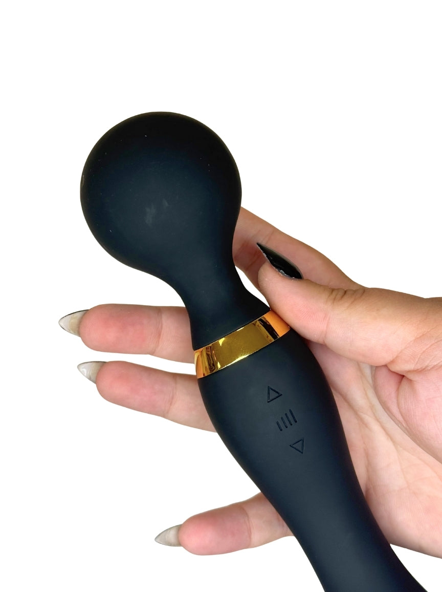 Black handheld device with gold accent held by a hand on a white background